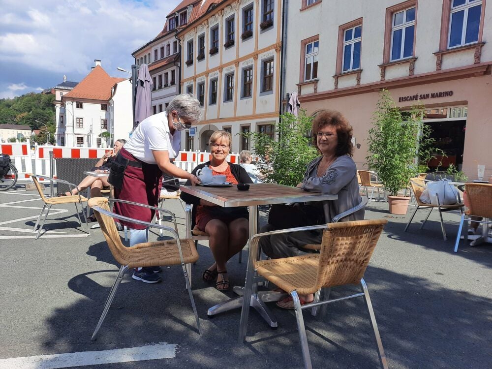 Steffi Porzig serviert Barbara Bobolowski und Susanne Schulz einen Eiscafé mitten auf der für Autos gesperrten Leipziger Straße.