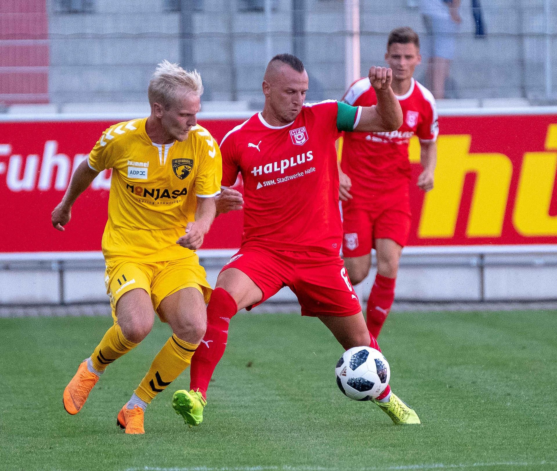 Halles Toni Lindenhahn (M.) gegen Andreas Oggesen (l.) im Testspiel des HFC gegen FC Fredericia (Dänemark) in Halle.