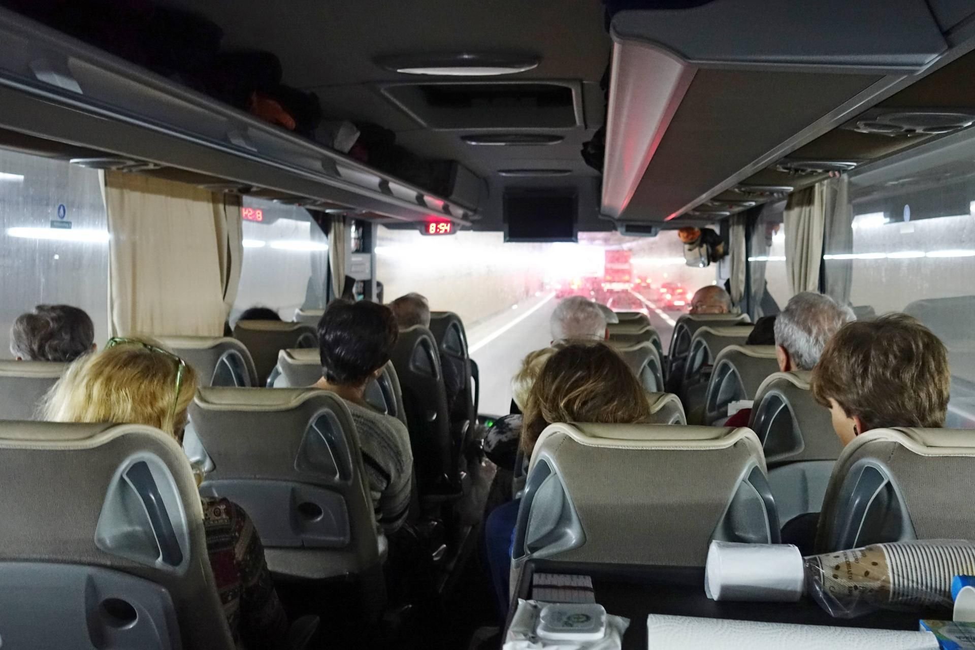 Menschen fahren in einem Reisebus durch einen Tunnel.