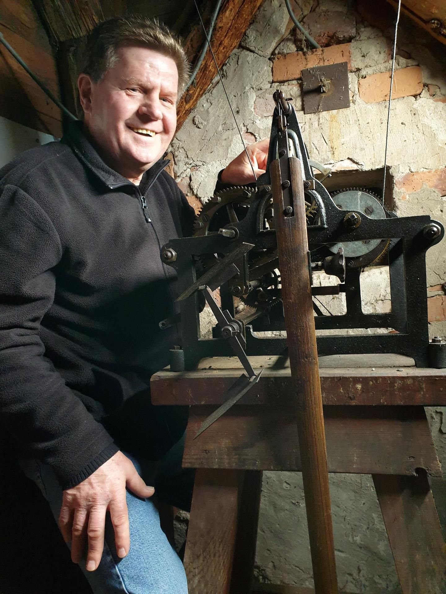 Hartmut Borghardt steht an der alten Uhr in der Schule.