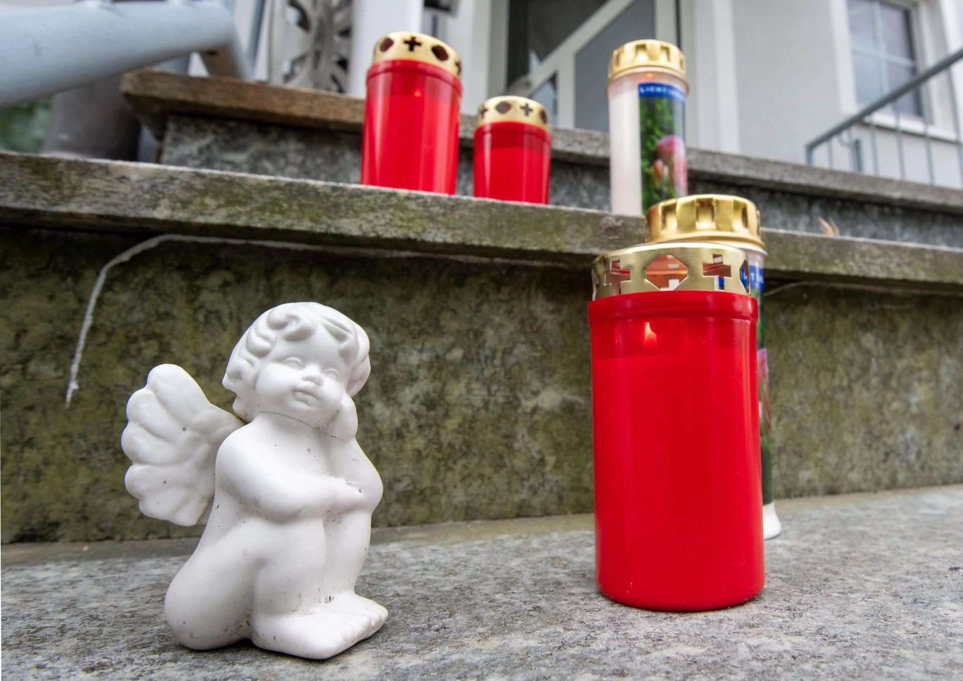 Kerzen und ein kleiner Engel stehen vor dem Hauseingang eines Hauses.