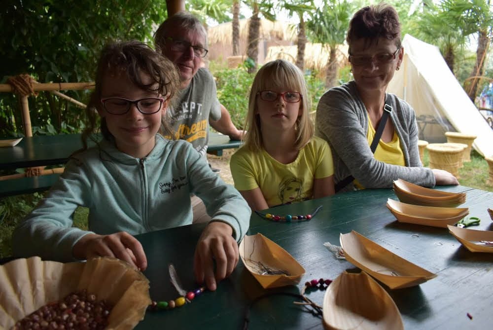 Alida (l.) und Leony (M.) basteln Indio-Schmuck aus Perlen und Federn.