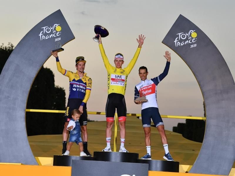 Der Zweitplatzierte Primoz Roglic (l-r) (mit seinem Sohn Lev), Tour-Sieger Tadej Pogacar und der Drittplatzierte Richie Porte feiern auf dem Podium. Foto: David Stockman/BELGA/dpa