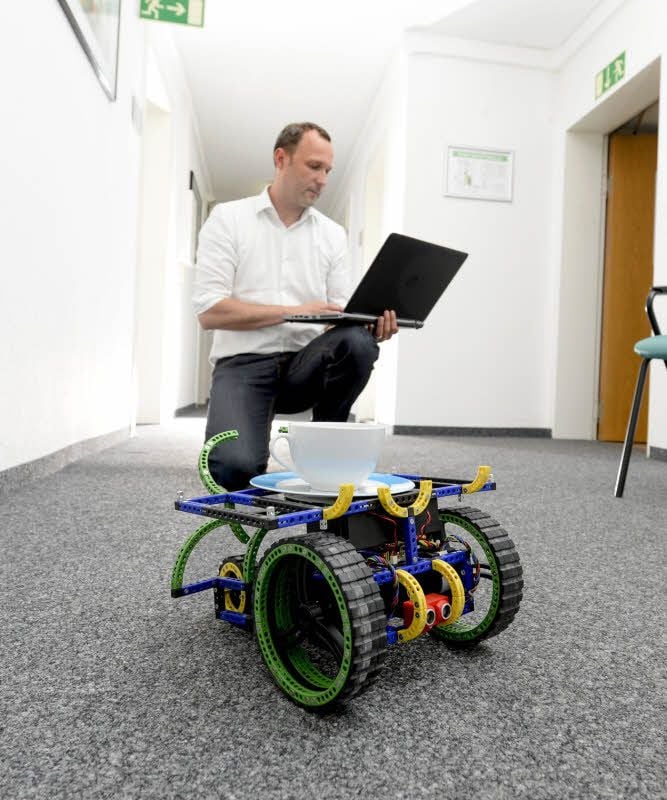 Patrick Jahn bedient einen kleinen Roboter, mit dem die Uniklinik in Halle bereits Versuche macht. Bald soll ein weiterer Roboter gekauft werden, der viel mehr Aufgaben erledigen kann.
