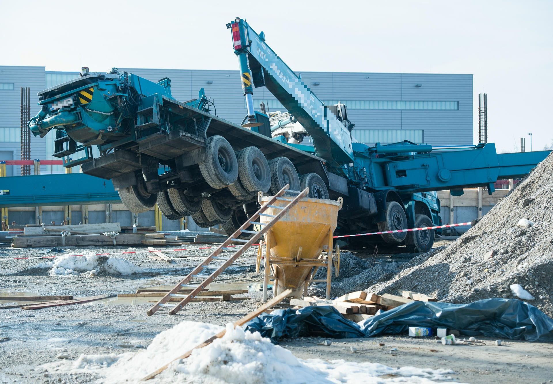 Ein umgekippter Schwerlaster mit Betonpumpe liegt auf einer Baustelle in Freising (Bayern).