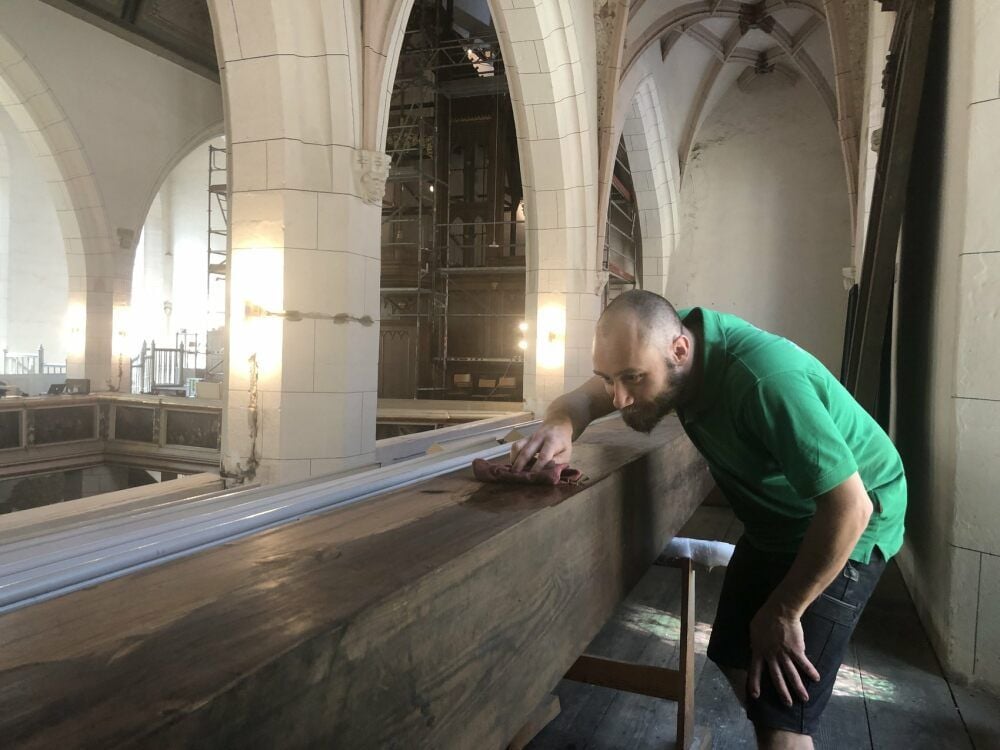 Fabian Zocher wischt mit einem feuchten Tuch den alten Staub von den in Weißenfels verbliebenen großen Orgelpfeifen.
