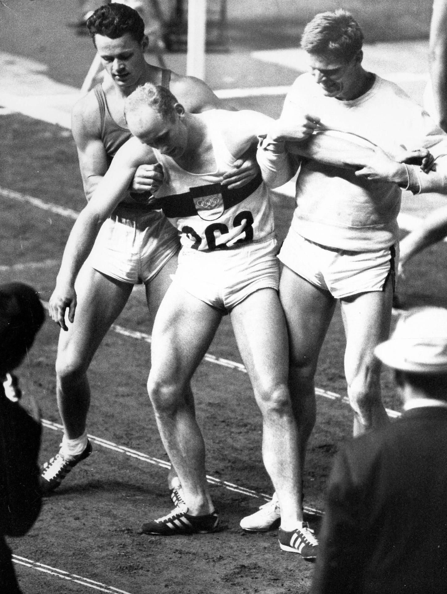 Die legendäre Szene: Zehnkämpfer Willi Holdorf muss nach seinem Triumph bei Olympia 1964 in Tokio im Zielbereich nach dem 1500-Meter-Lauf gestützt werden.