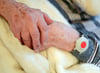 Eine pflegebedürftige Frau trägt einen Notknopf am Handgelenk.