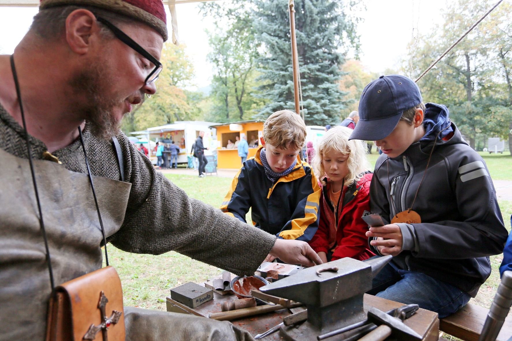 Kinder schauen einem Schmied beim Runkelrübenfest in Thale bei der Arbeit.