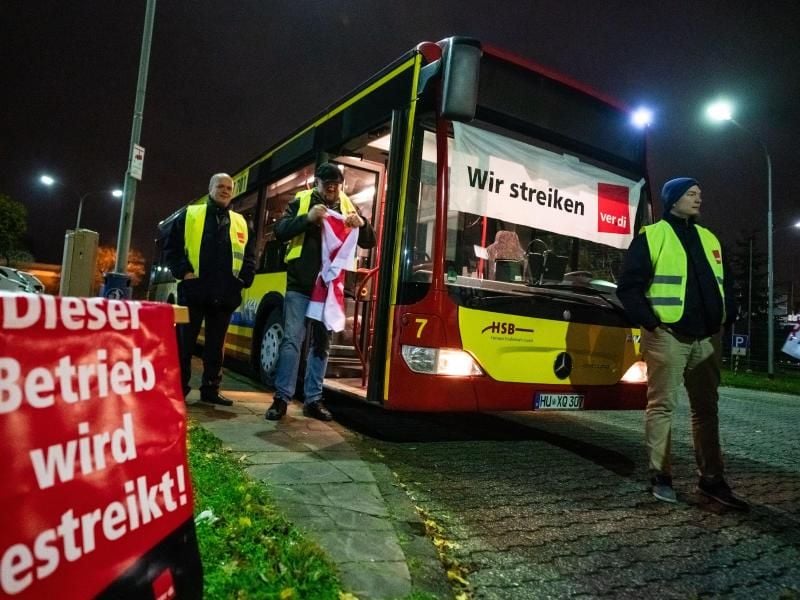Busfahrer stehen neben einem Fahrzeug mit einem Banner vor der Frontscheibe. Foto: Frank Rumpenhorst/dpa