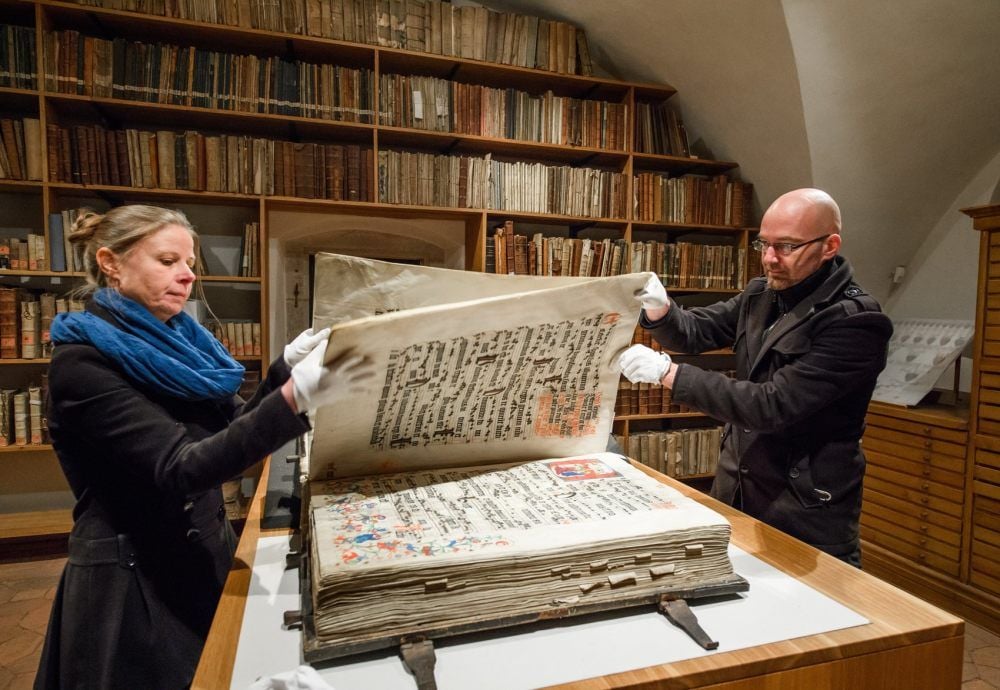 Seitenspiel für vier Hände: Dombibliothekarin Cordula Strehl und Domarchivar Matthias Ludwig beim Wenden von Seiten eines Chorbuchs