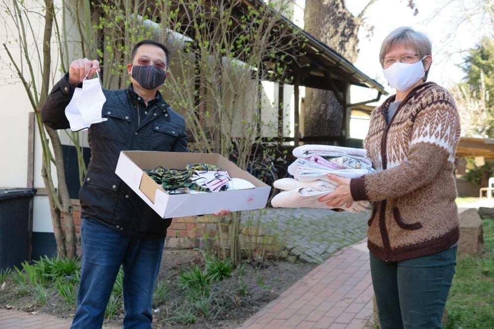Quoc An Lam vom Vietnamesischen Verein brachte Cornelia Muntschick genähte Gesichtsmasken und nahm von ihr Baumwollstoffe entgegen.