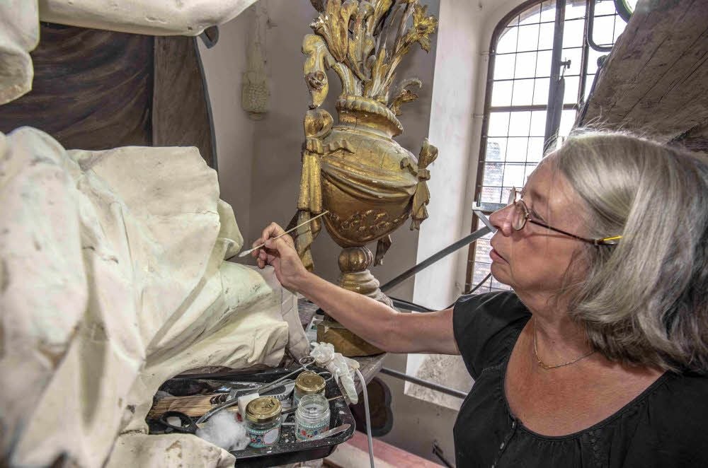 Susanne Gerlach säubert mit einem Wattestäbchen eine Engelsfigur.