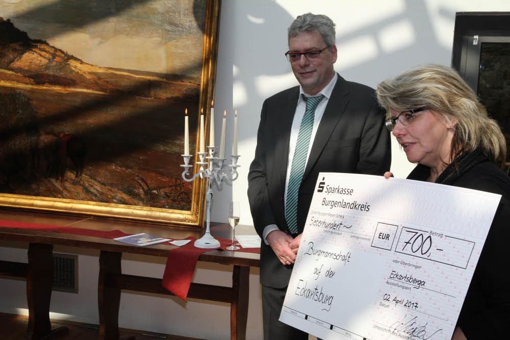 Sylvia Schütze von der Burg-Pächterfamilie überreicht Christof Clanzett von der Burgmannschaft einen Scheck für die Bildrestaurierung.