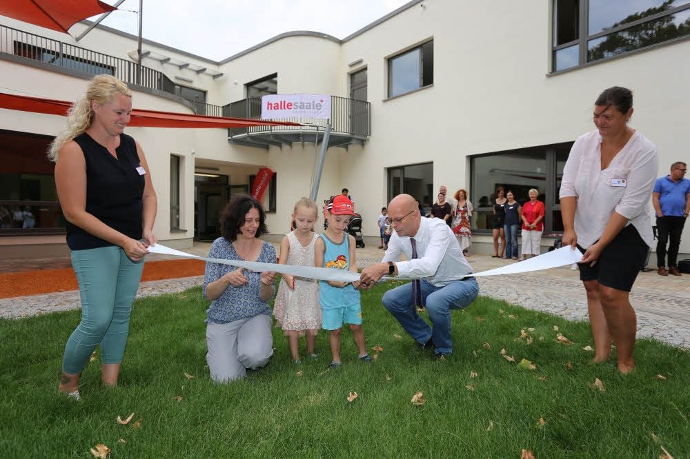 Oberbürgermeister Bernd Wiegand zerschneidet zusammen mit Kita-Leiterin Jacqueline Gawlitta und Mia und John das Eröffnungsband.