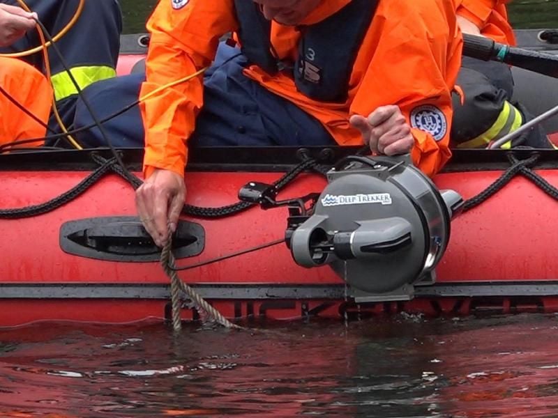 Ein Helfer des Technischen Hilfswerks hält einen Tauchroboter über den Aje-See. Foto: Keutz TV-News/dpa