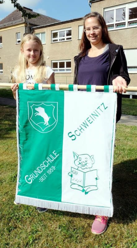 Ideengeberin Aaliyah Knochmuß (links) und Kunstlehrerin Yvonne Schlobach präsentieren die neue Fahne der Grundschule.