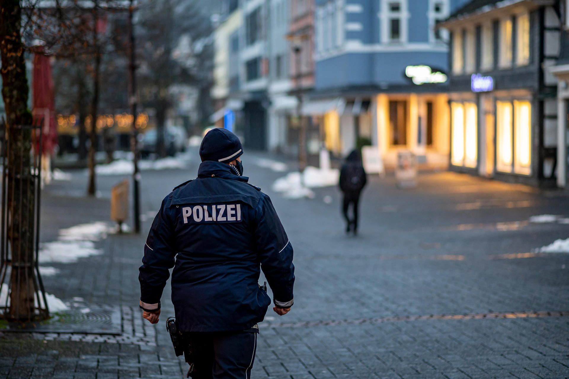 Ein Polizist mit Mund-Nase-Schutz geht durch die Innenstadt von Gummersbach. Wegen hoher Corona-Infektionszahlen hat der Oberbergische Kreis eine nächtliche Ausgangssperre sowie eine Begrenzung der sozialen Kontakte auch im privaten Bereich beschlossen.