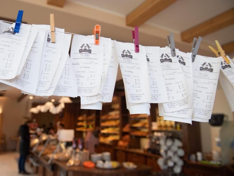 Zahlreiche Kassenzettel hängen in einer Bäckerei an einer Leine. Foto: Sebastian Kahnert/dpa-Zentralbild/dpa
