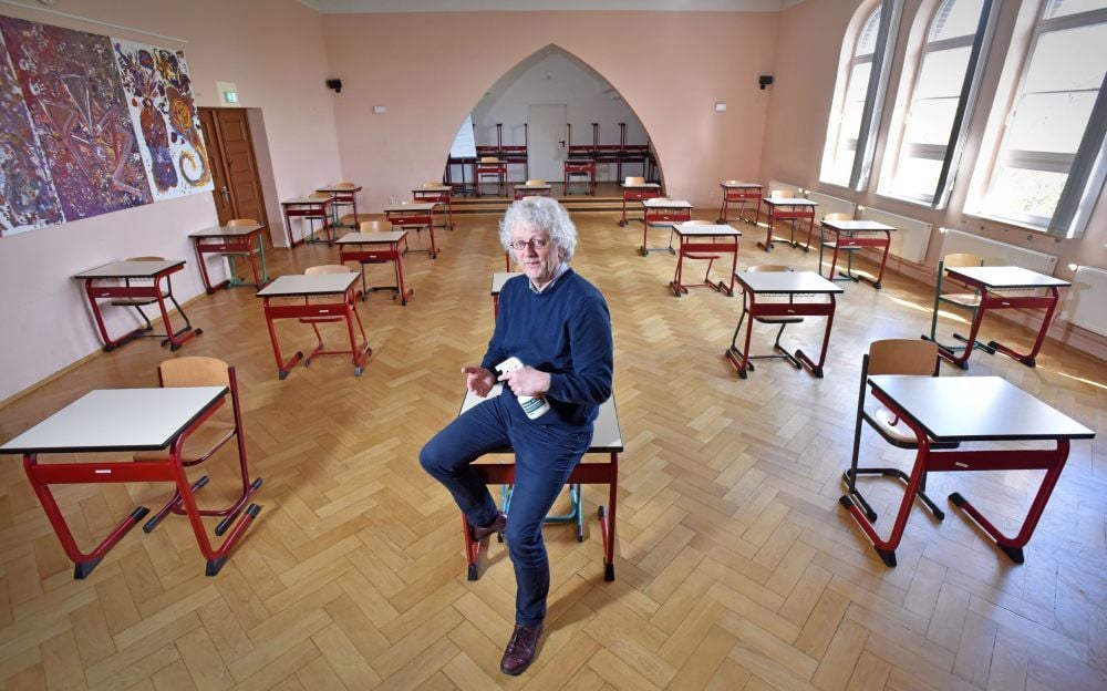 Schulleiter Günter Eckert in der Aula des Gymnasiums. Auch in diesem Raum wurden trotz Coronakrise Mathematik-Vorprüfungen für das Abitur 2020 geschrieben. Eckert zeigt eine Flasche mit Desinfektionsmittel. Jeder Schüler musste sich vor Betreten des Raumes die Hände desinfizieren.