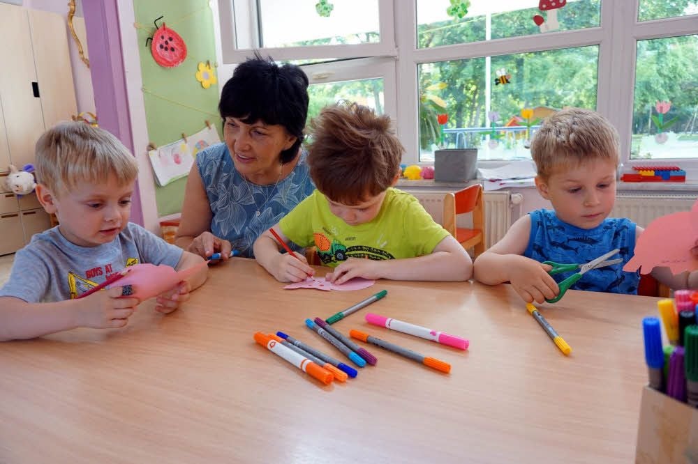 Martina Hübner, Leiterin der evangelischen Kindertagesstätte „Regenbogen“, bastelt mit Marius, Leonas und Marek (v.l.) an den Glücksbringern.