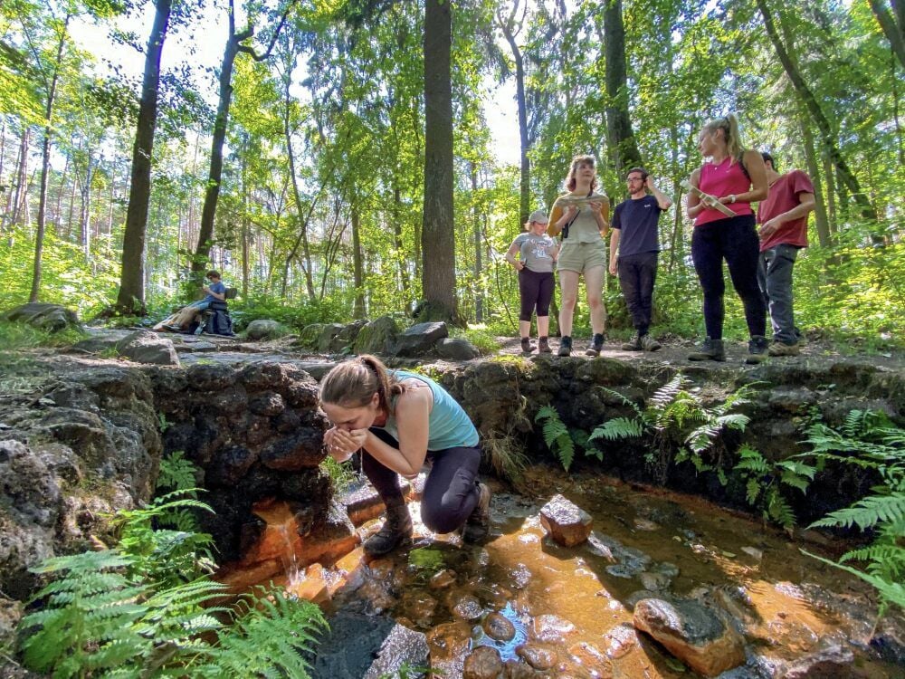 Eine Studentin kostet das frische Quellwasser. Der Gesundbrunnen in der Dübener Heide ist zuvor gereinigt und entschlammt worden.