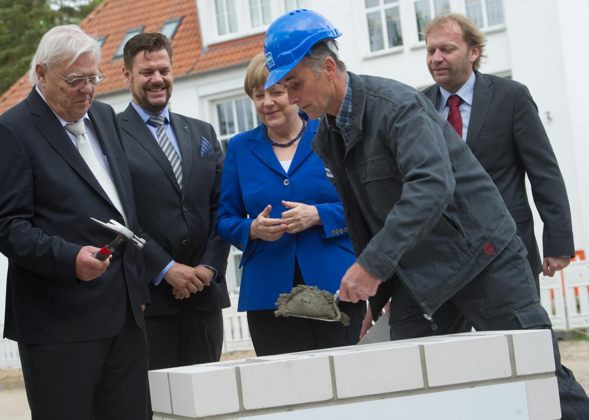 Hartmut Klocke (links) mit seinen beiden Söhnen Stefan Klocke und Carsten Klocke sowie Bundeskanzlerin Angela Merkel während der Grundsteinlegung für ein neues Forschungsgebäude der Firma IDT Biologika.