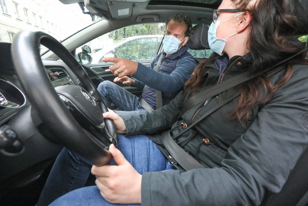 Mit Mund-Nasen-Schutz gibt Fahrlehrer Mandes Nadler der Fahrschülerin letzte Anweisungen.