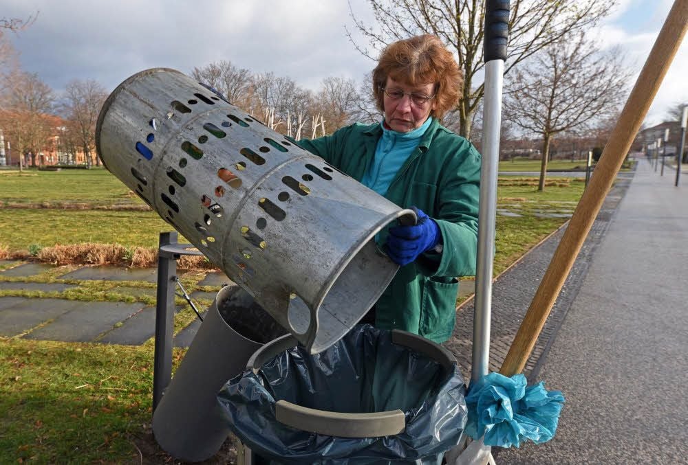 Barbara Fehse entleert die Papierkörbe auf der Herrenbreite in Aschersleben.