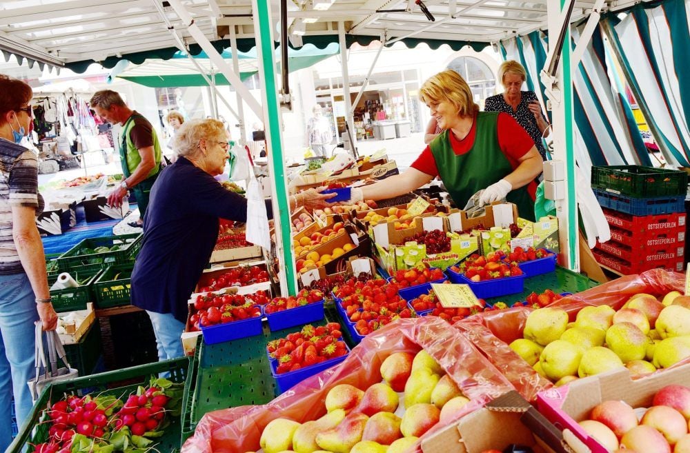Markttreiben in Eisleben: Eine Kundin kauft Erdbeeren bei Kerstin (rechts) und Ingo Glade (l.).