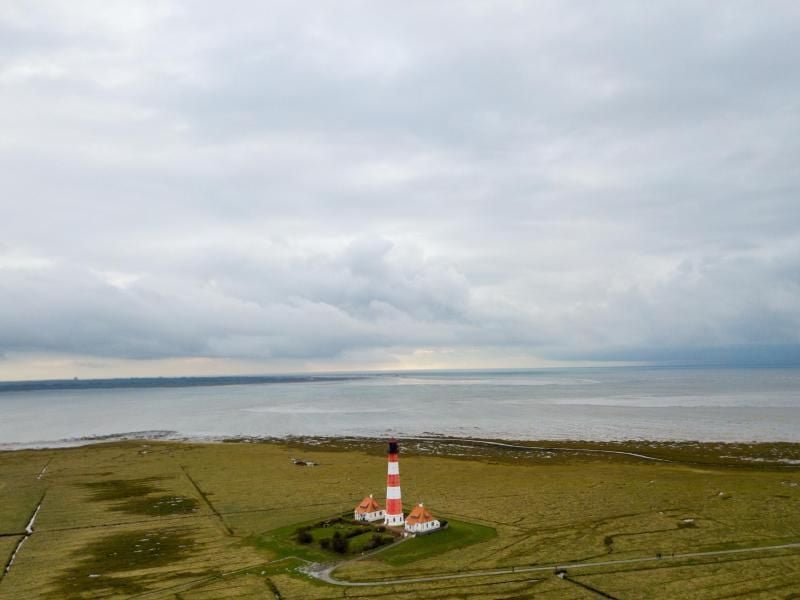 Regenwolken ziehen am Leuchtturm Westerheversand in Westerhever über das Wattenmeer. Foto: Axel Heimken/dpa/Archivbild