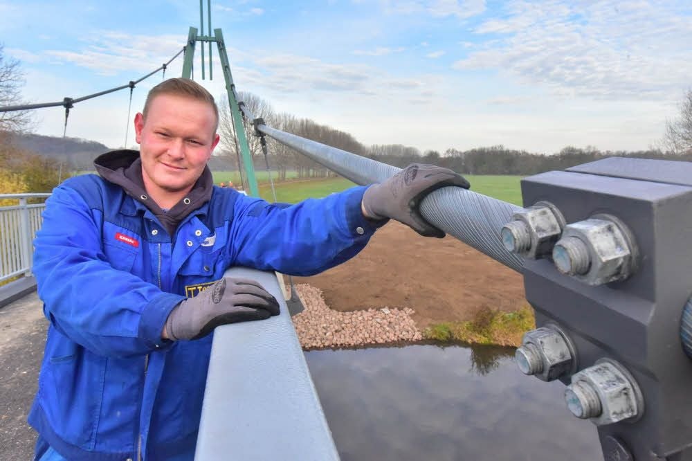 Marcus Nagel umfasst eines der rund neun Zentimeter starken Stahlseile, an denen die Brücke hängt.