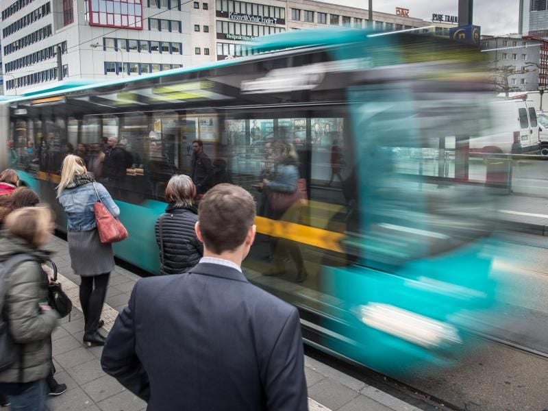 Fahrgäste stehen an einer Bushaltestelle in der Innenstadt von Frankfurt am Main. Foto: Frank Rumpenhorst/Archivbild