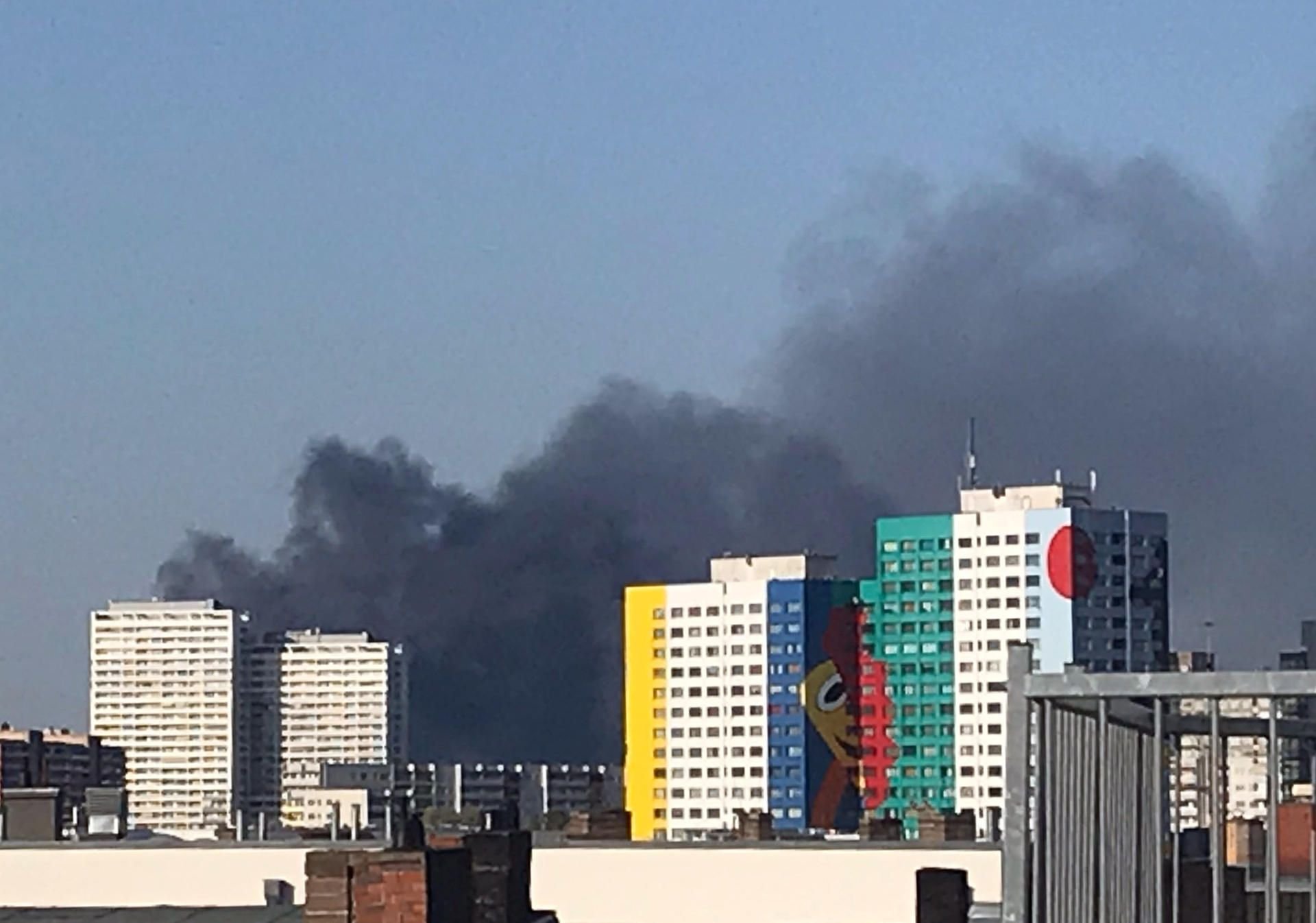 Dunkler Rauch steigt hinter den Hochhäusern nahe der Storkower Straße in Berlin auf.