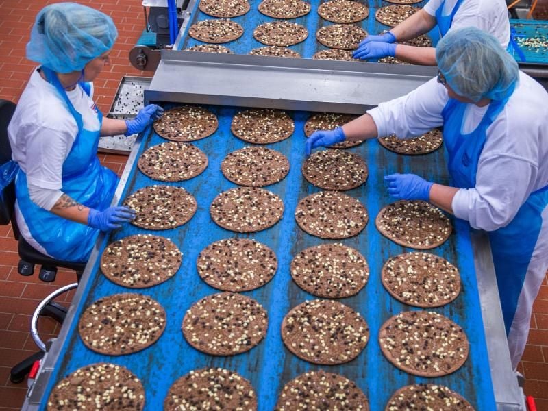 Mitarbeiterinnen belegen im Pizzawerk der Firma Dr. Oetker kakaohaltige Pizzaböden mit Schokoladensplittern. Die Schokoladenpizza wird nach zwei Jahren eingestellt. Foto: Jens Büttner/dpa-Zentralbild/dpa