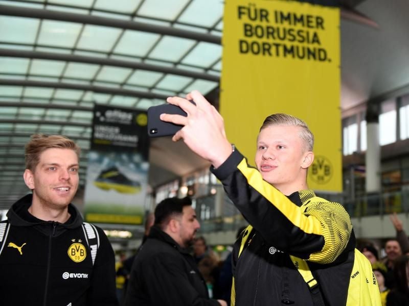 Erling Haaland (r) macht am Dortmunder Flughafen mit seinem Handy ein Selfie von sich. Foto: David Inderlied/dpa