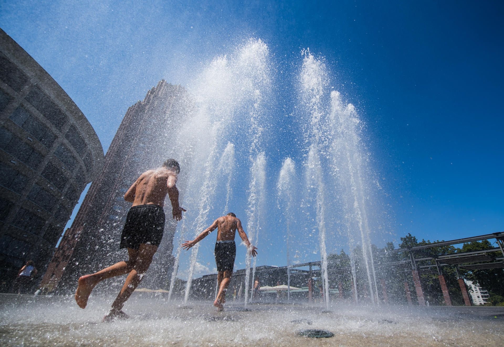 Jungen Menschen erfrischen sich an einem Brunnen in Frankfurt.