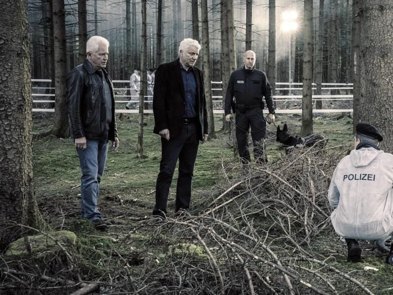Die Kriminalhauptkommissare Ivo Batic (l-r, Miroslav Nemec) und Franz Leitmayr (Udo Wachtveitl) mit Kollegen (Komparsen) betrachten den Fundort von Emils Fahrrad im Wald. Foto: Hendrik Heiden/BR/Bavaria Fiction GmbH/dpa