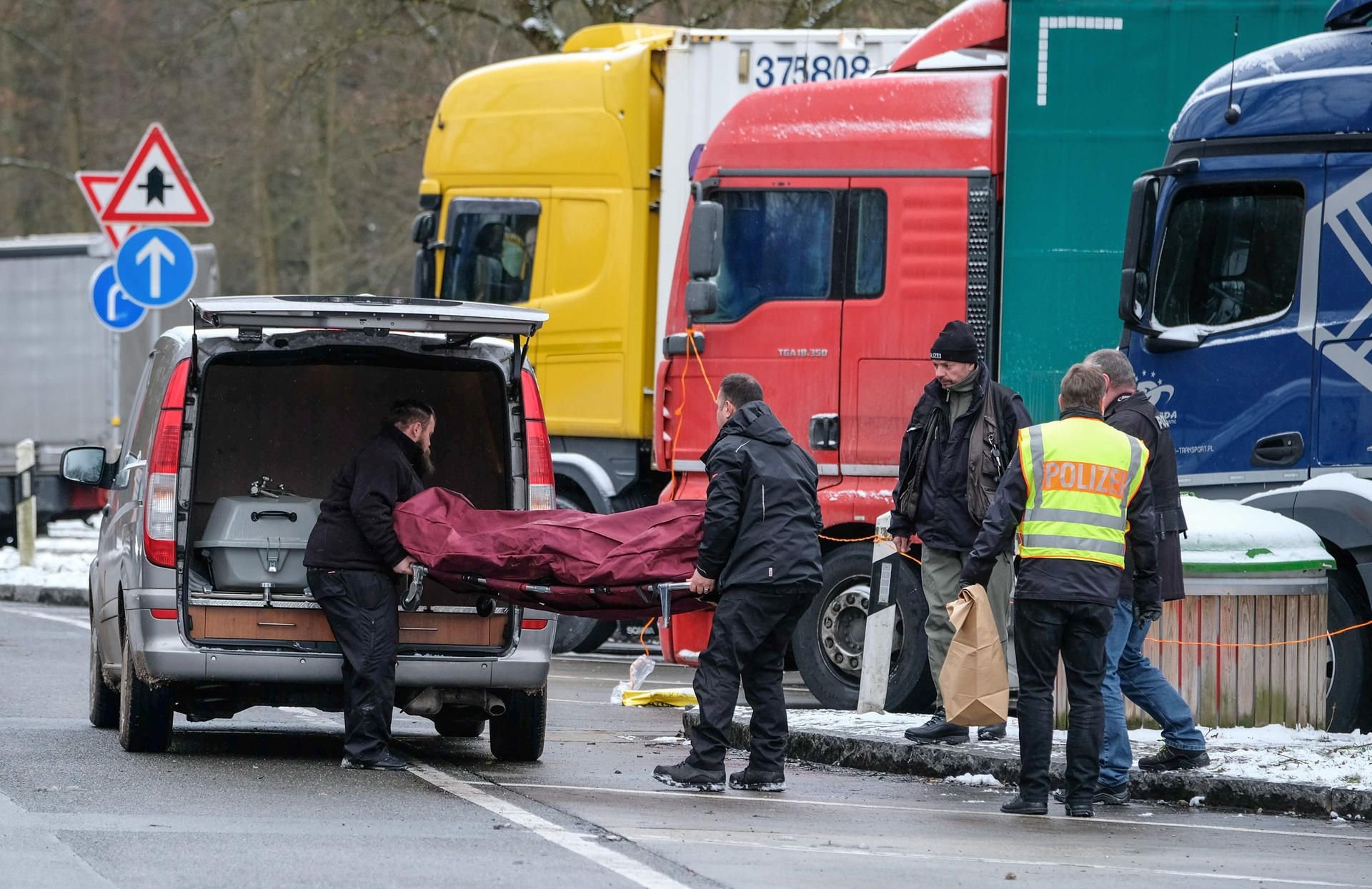 Die Leiche des Lkw-Fahrers auf dem Rastplatz wird in einen Leichenwagen getragen.