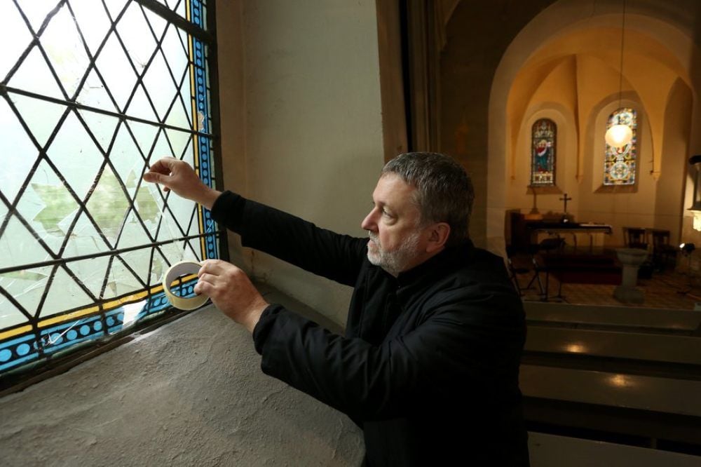Notdürftig klebt Pfarrer Tobias Wessel die Löcher in den Fenstern der Kirche in Preußlitz mit Folie und Klebeband zu, damit es nicht reinregnet.