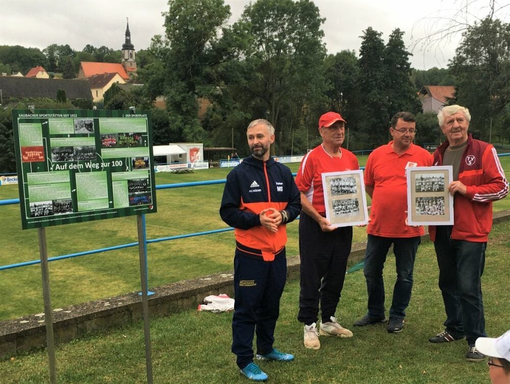 Sportkoordinator Michael Schubel (v.l.), der langjährige Vorsitzende Bernd Sperling, Vorstandsmitglied Marco Dietrich und Rudolf Schaks, bereits seit 68 Jahren TV-Mitglied, bei der Enthüllung der Infotafel auf dem Saubacher Sportplatz.