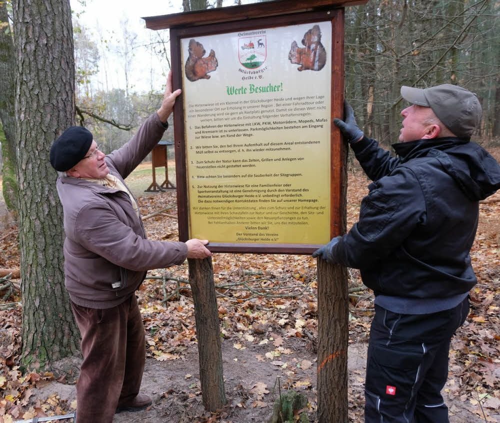 Vorsitzender Erhard Fritzsche (links) und Rainer Giersch vom Heimatverein Glücksburger Heide bringen auf der Jessener Hirtenwiese eine neue Schautafel mit fünf wichtigen Verhaltensregeln an.