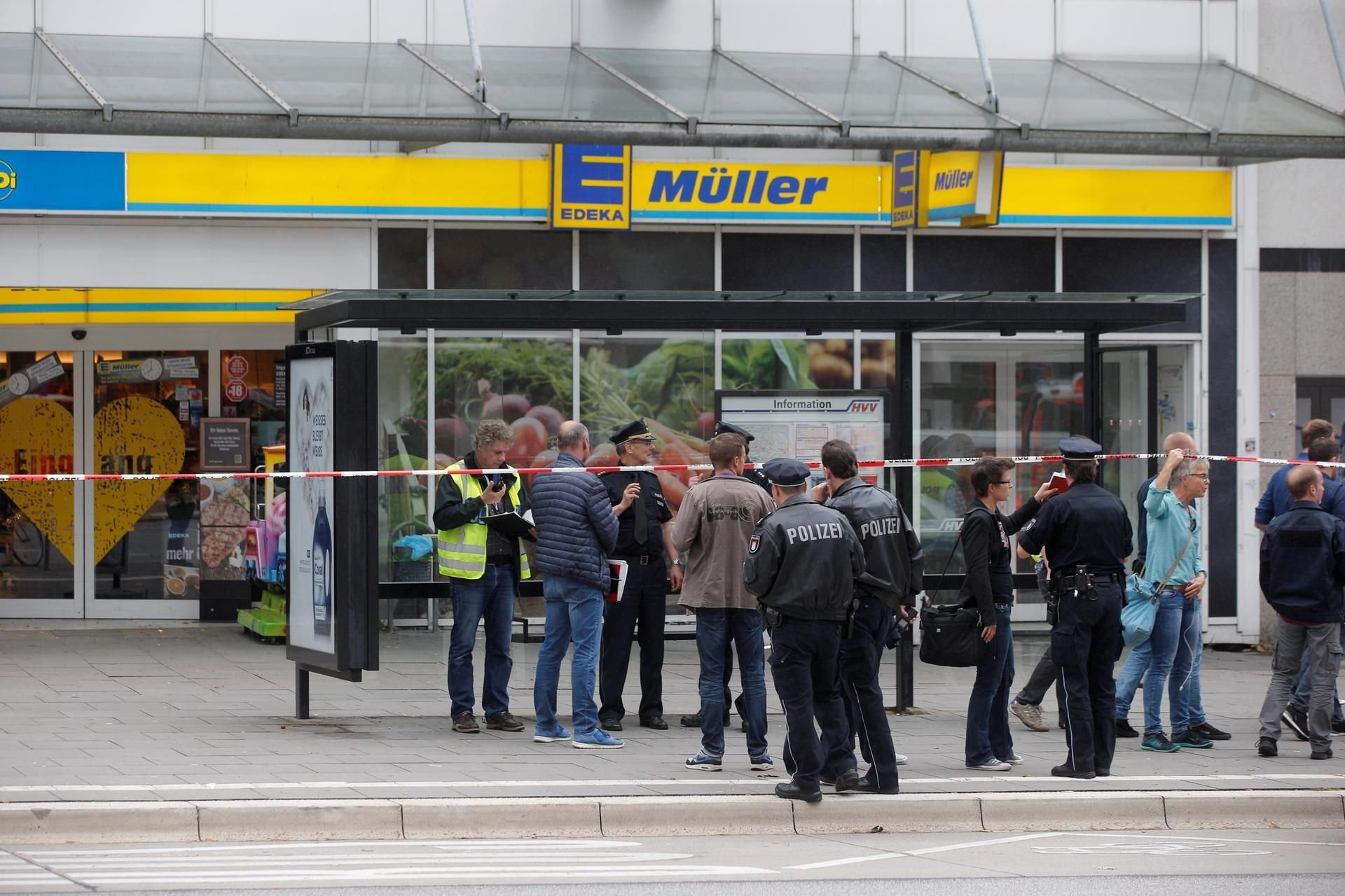 Einsatzkräfte der Polizei stehen am 28.07.2017 nach einer Messerattacke in einem Supermarkt in Hamburg am Tatort.