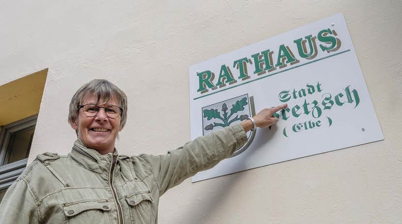 Diana Skowronek zeigt das Stadt-Schild am Pretzscher Rathaus.