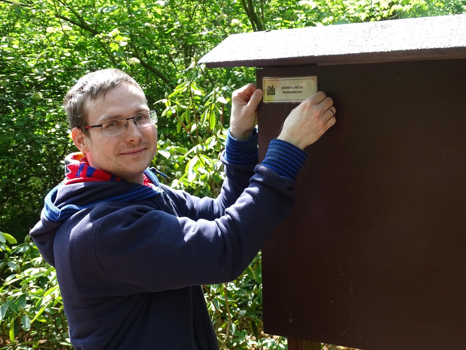 Andreas Hesse bringt sein Patenschild im Tierpark Dessau an.