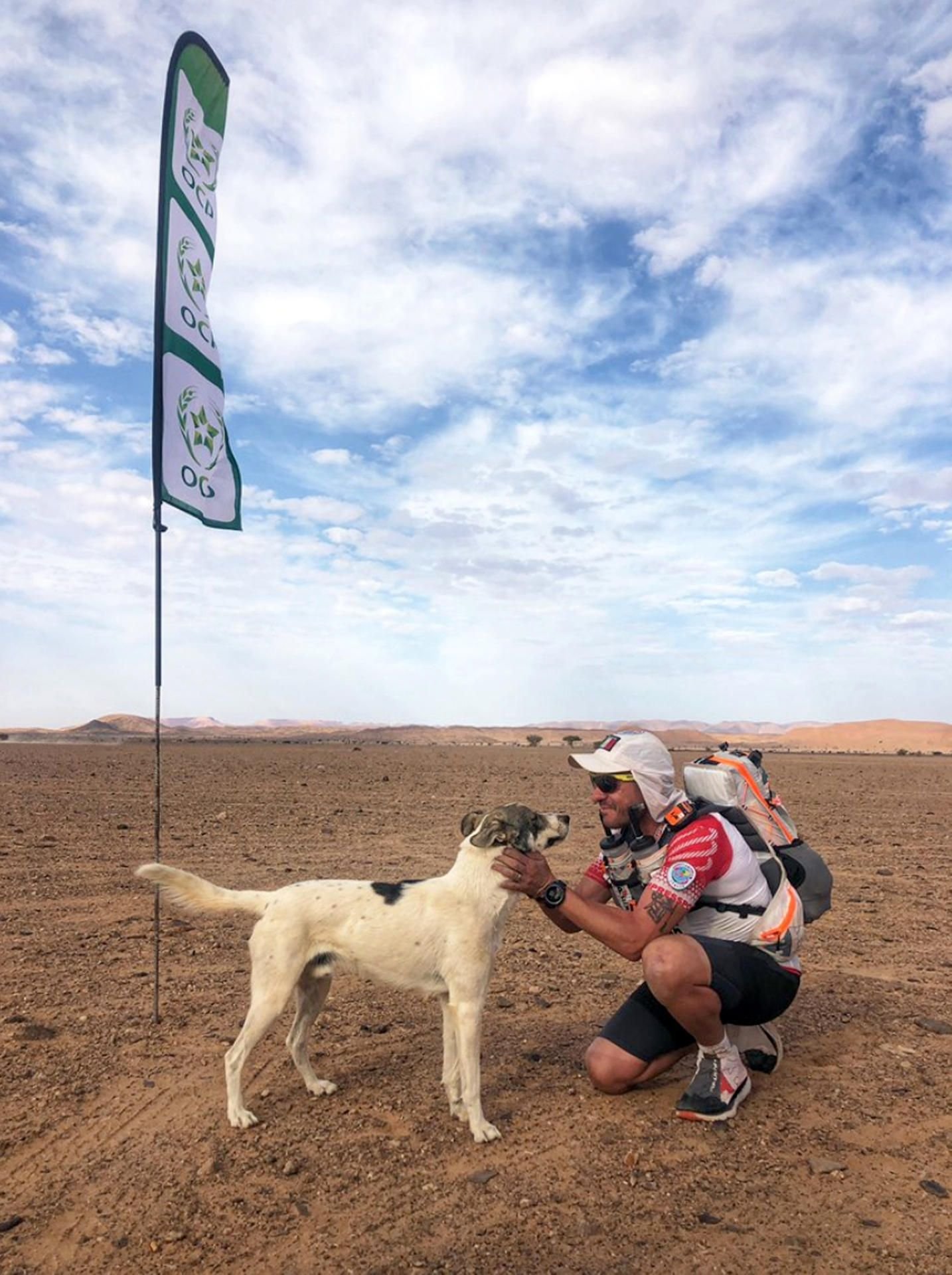 Ein Läufer streichelt Hund Cactus auf der vierten Etappe des „Marathon des Sables“.