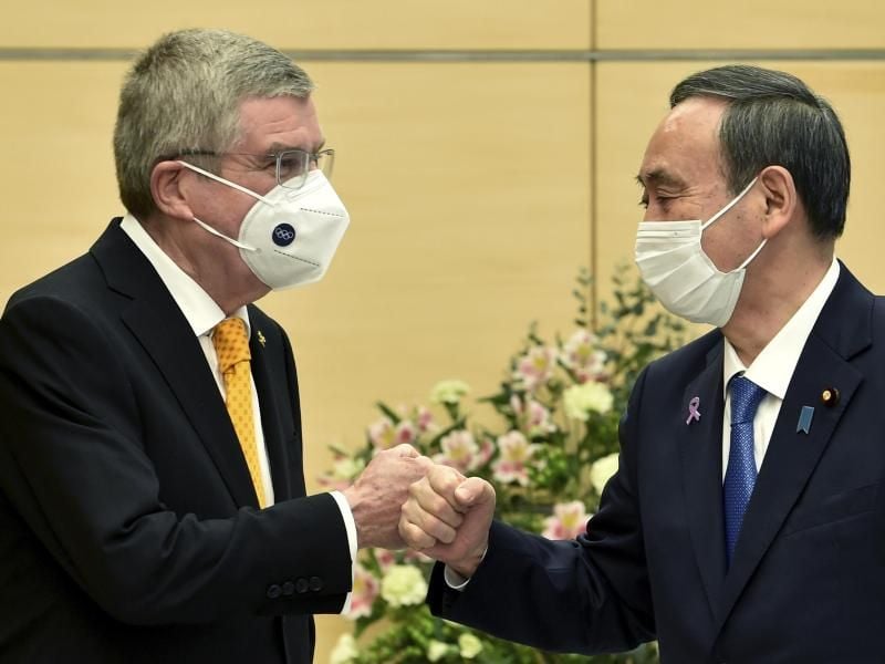 Thomas Bach (l), Präsident des Internationalen Olympischen Komitees, und Yoshihide Suga, Premierminister von Japan, begrüßen sich. Foto: Kazuhiro Nogi/AFP Pool/AP/dpa