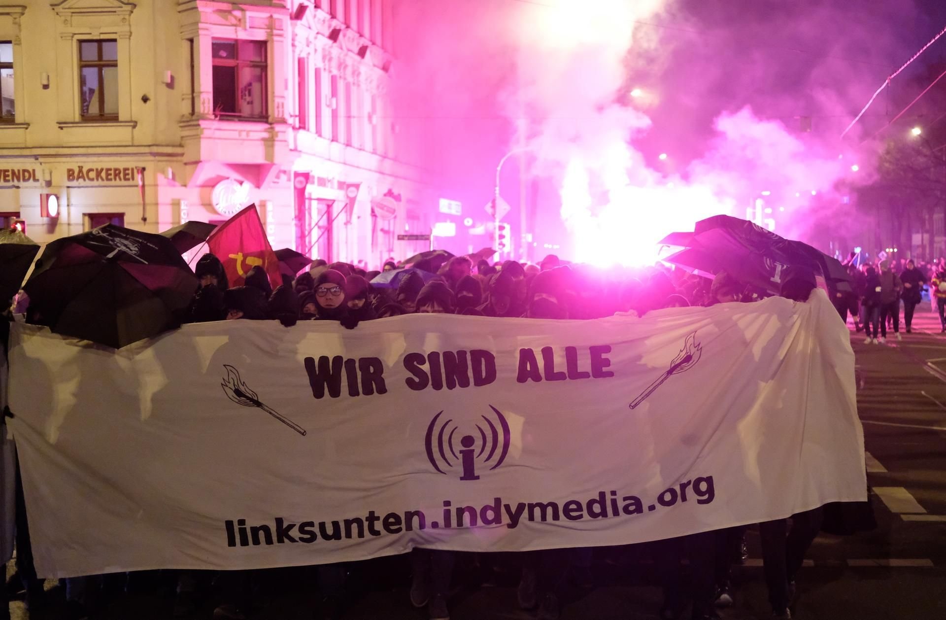 Teilnehmer einer linken Demonstration tragen ein Transparent mit der Aufschrift „wir sind alle linksunten.indymedia.org“ und zünden Pyrotechnik.