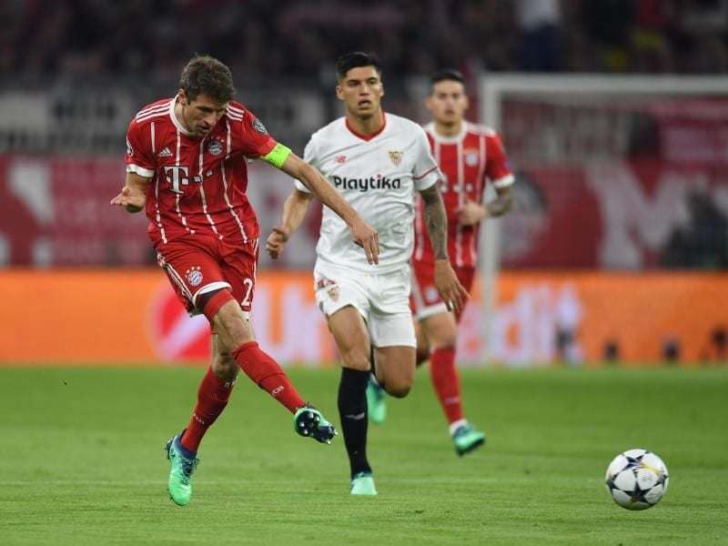 Bayern-Kapitän Thomas Müller (l) zieht ab, Sevillas Carlos Joaquin Correa hat das Nachsehen. Foto: Sven Hoppe