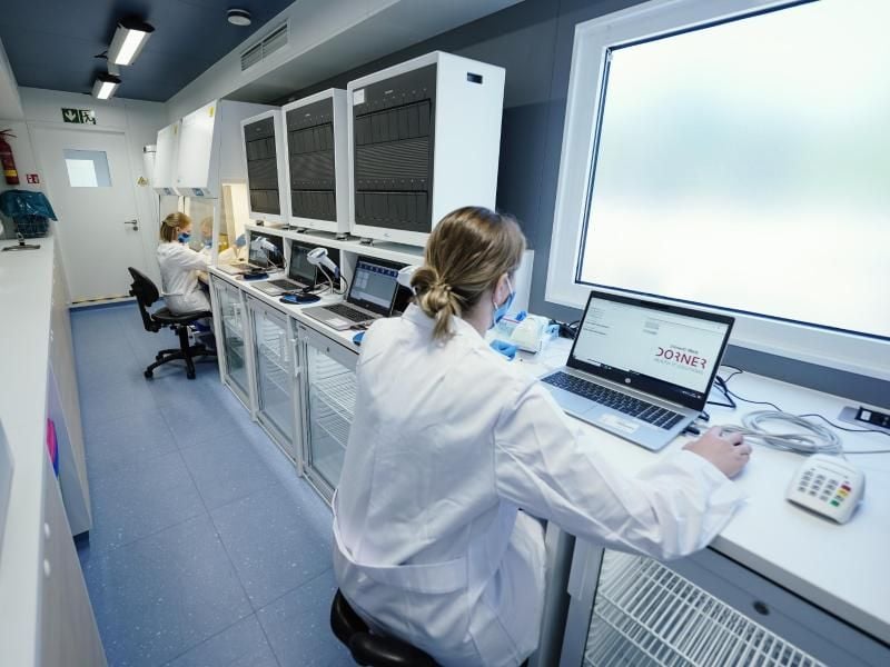 Zwei Mitarbeiterinnen demonstrieren die Arbeit im Labor einer mobilen Corona-Teststation. Foto: Uwe Anspach/dpa/Symbolbild